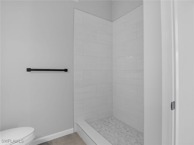 bathroom featuring a tile shower and toilet