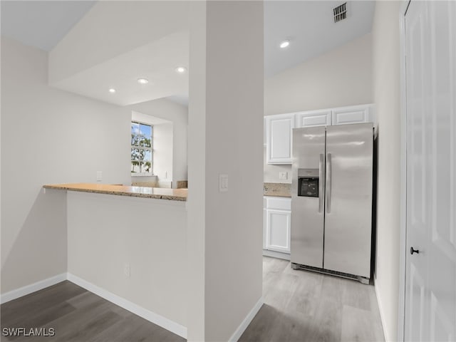 kitchen featuring white cabinets, vaulted ceiling, stainless steel fridge, and light hardwood / wood-style floors