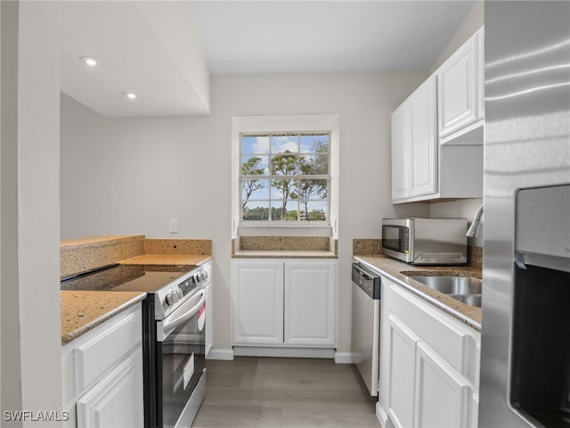 kitchen featuring white cabinets, stainless steel appliances, light hardwood / wood-style flooring, and light stone countertops