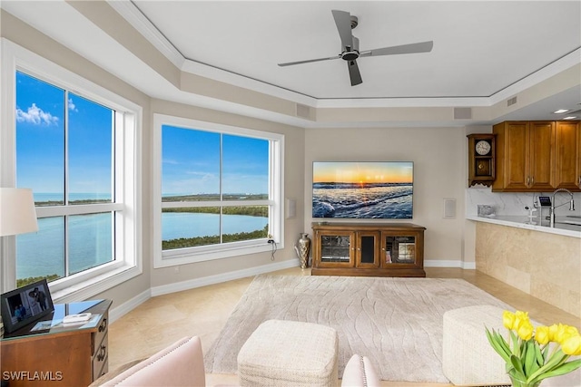 living room featuring ceiling fan, ornamental molding, and a tray ceiling