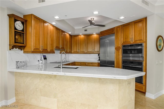 kitchen featuring a raised ceiling, kitchen peninsula, appliances with stainless steel finishes, and ceiling fan