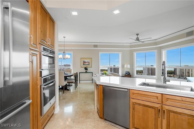 kitchen with decorative light fixtures, sink, stainless steel appliances, and ceiling fan with notable chandelier