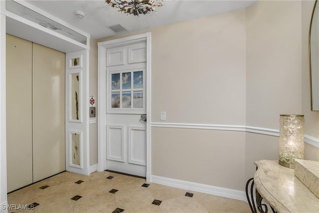 entryway with light tile patterned flooring, an inviting chandelier, and elevator