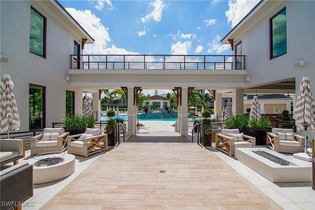 view of patio with a balcony and an outdoor living space with a fire pit