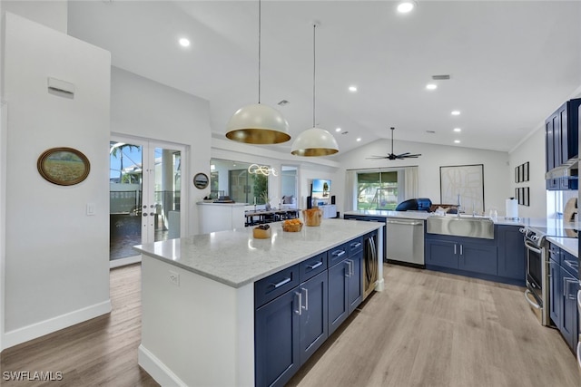 kitchen featuring ceiling fan, appliances with stainless steel finishes, light stone countertops, a kitchen island, and sink