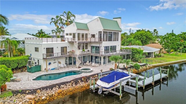 back of house featuring a pool with hot tub, a balcony, a patio area, and a water view