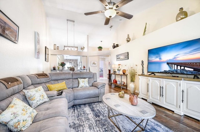 living room with a towering ceiling, ceiling fan, and dark hardwood / wood-style floors