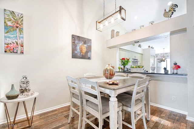 dining area with a high ceiling and dark hardwood / wood-style floors