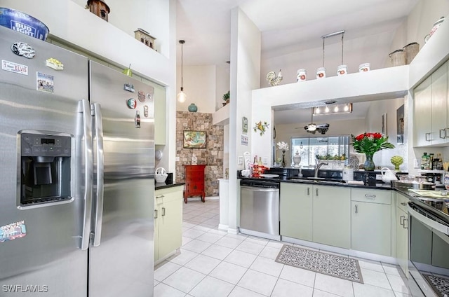 kitchen featuring stainless steel appliances, a high ceiling, decorative light fixtures, light tile patterned flooring, and sink