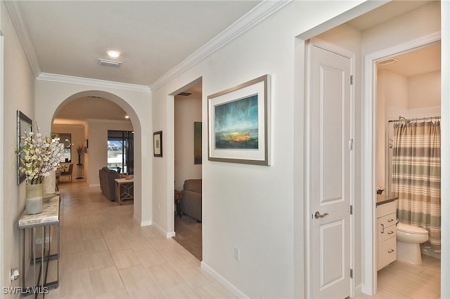 hall featuring crown molding, baseboards, arched walkways, and visible vents