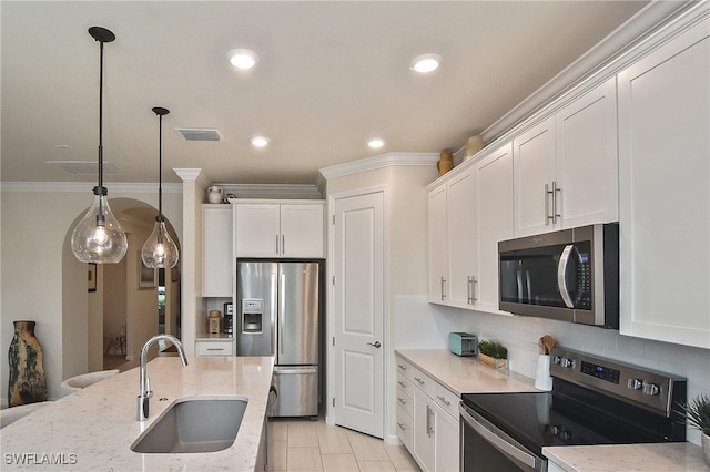 kitchen with white cabinetry, appliances with stainless steel finishes, decorative light fixtures, light stone counters, and sink