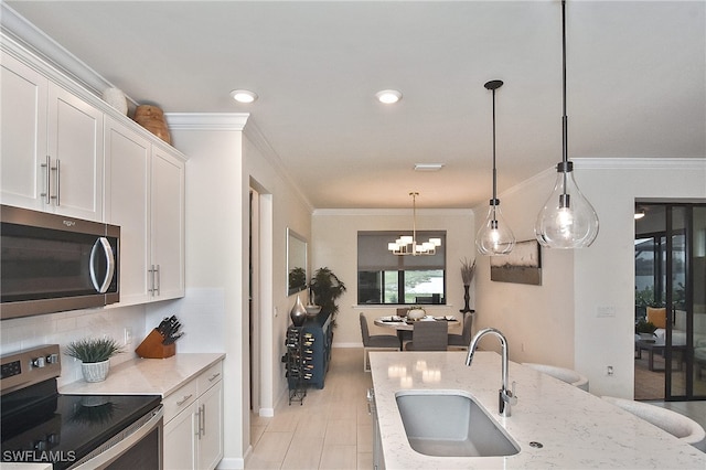 kitchen with a sink, stainless steel appliances, tasteful backsplash, and white cabinetry