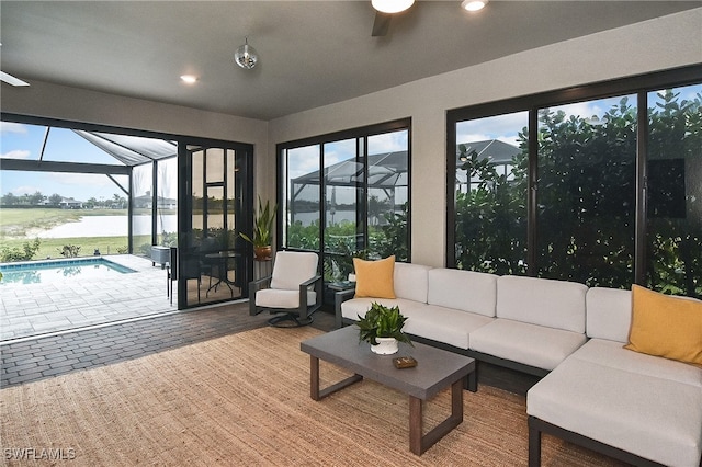 sunroom with a ceiling fan and a water view