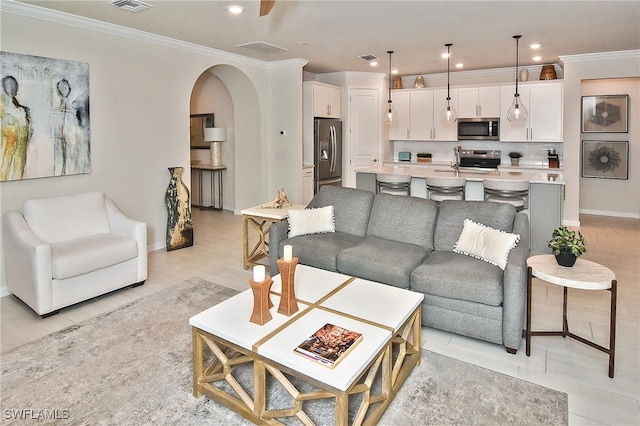 living room with arched walkways, visible vents, recessed lighting, and ornamental molding