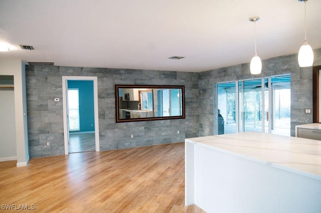 kitchen featuring tile walls, hanging light fixtures, and light wood-type flooring