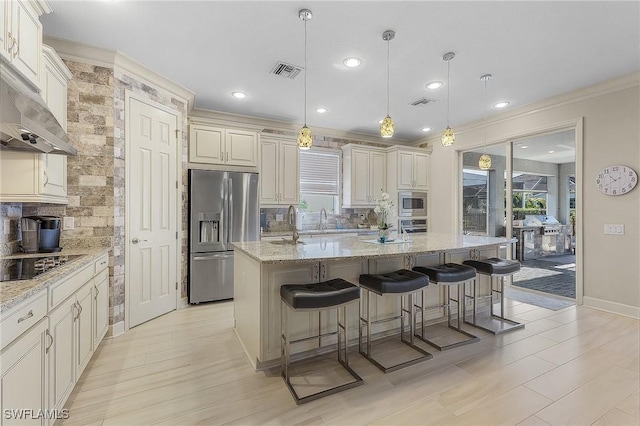 kitchen featuring stainless steel appliances, backsplash, decorative light fixtures, and a kitchen island with sink