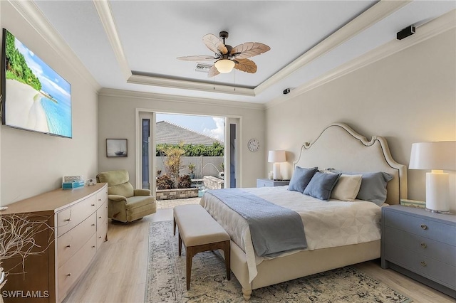 bedroom featuring light hardwood / wood-style floors, ceiling fan, access to outside, a tray ceiling, and ornamental molding