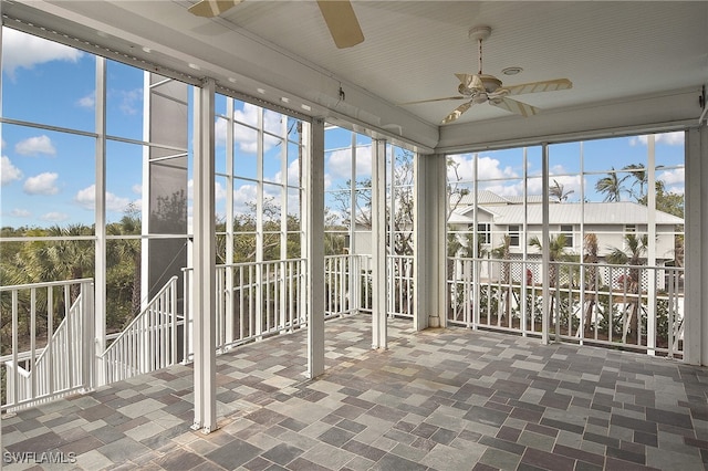 unfurnished sunroom featuring ceiling fan and a wealth of natural light