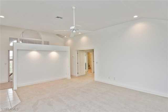 empty room with light carpet, ceiling fan, and high vaulted ceiling