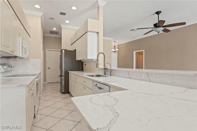 kitchen featuring white appliances, kitchen peninsula, light stone counters, crown molding, and sink