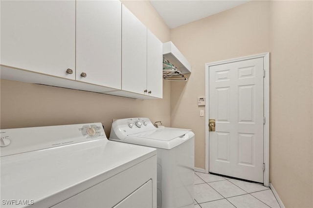 laundry area with separate washer and dryer, cabinets, and light tile patterned floors