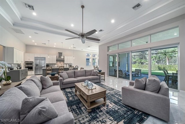 living room with ceiling fan, ornamental molding, and a high ceiling