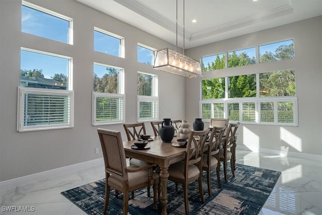 dining area featuring a raised ceiling, an inviting chandelier, and ornamental molding