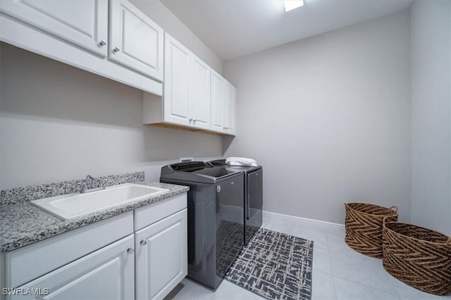 clothes washing area featuring sink, cabinets, light tile patterned flooring, and washer and dryer