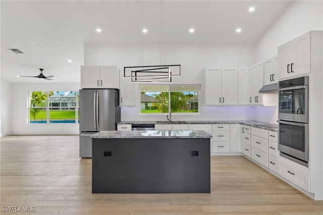 kitchen featuring a center island, light wood-type flooring, white cabinets, appliances with stainless steel finishes, and ceiling fan