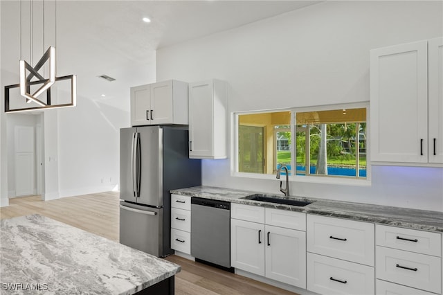 kitchen with light hardwood / wood-style floors, stainless steel appliances, light stone counters, sink, and white cabinetry