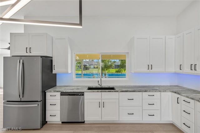 kitchen with sink, stainless steel appliances, white cabinets, and light stone counters