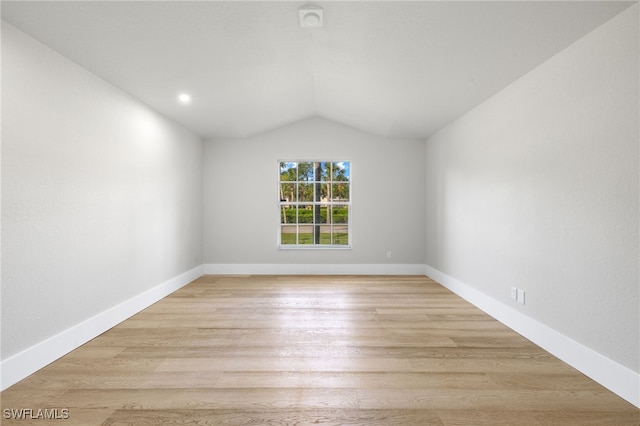 spare room with lofted ceiling and light wood-type flooring