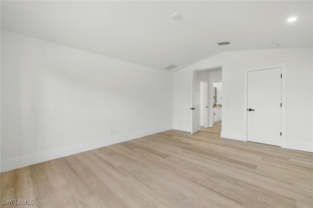 spare room with light hardwood / wood-style floors and lofted ceiling