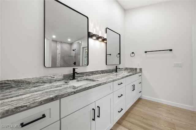 bathroom featuring wood-type flooring, walk in shower, and vanity