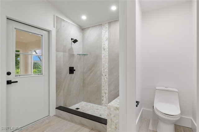 bathroom featuring toilet, tiled shower, and hardwood / wood-style floors