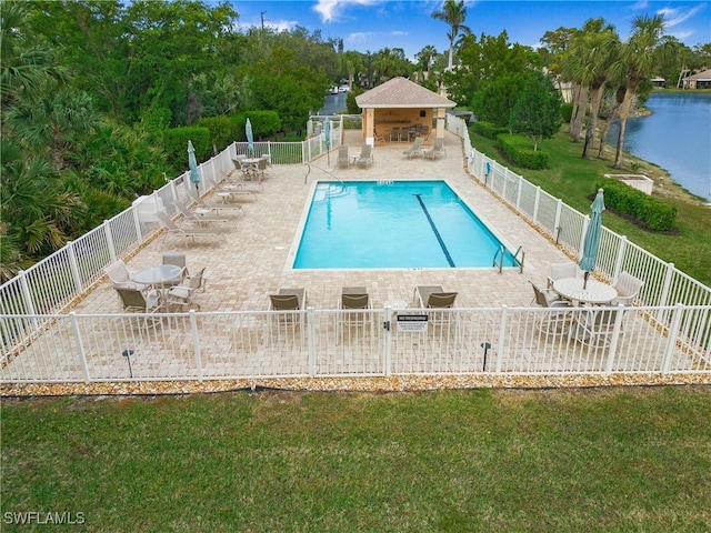 view of swimming pool featuring a yard, a patio, and a water view