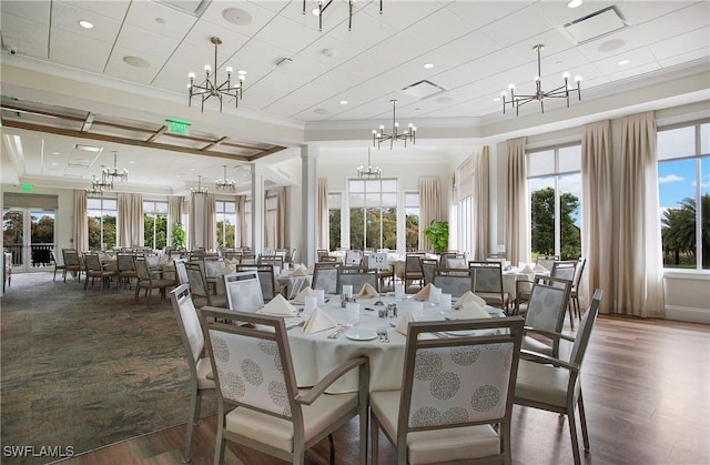 dining area featuring decorative columns, ornamental molding, dark hardwood / wood-style floors, and an inviting chandelier