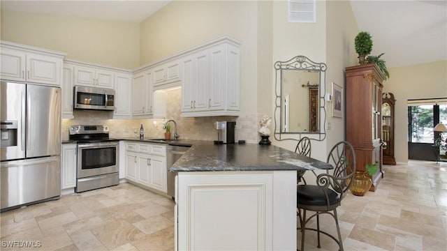 kitchen featuring sink, white cabinetry, high vaulted ceiling, appliances with stainless steel finishes, and kitchen peninsula