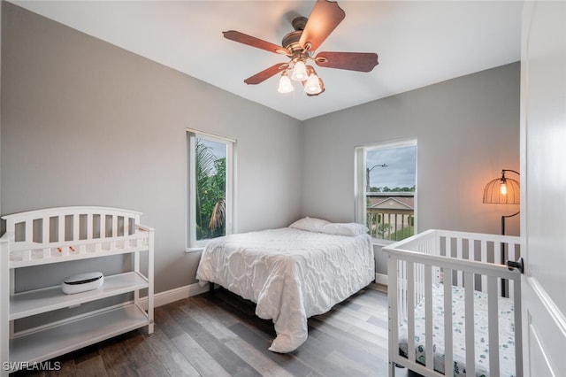 bedroom with ceiling fan, dark hardwood / wood-style floors, and multiple windows