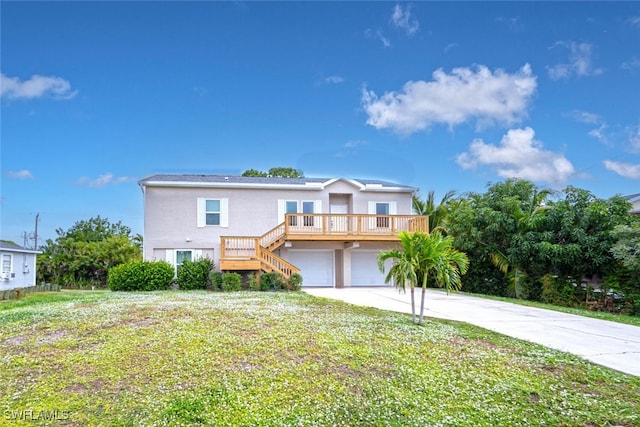 front facade featuring a front yard, a wooden deck, and a garage