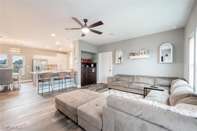 living room featuring light wood-type flooring, ceiling fan, and sink