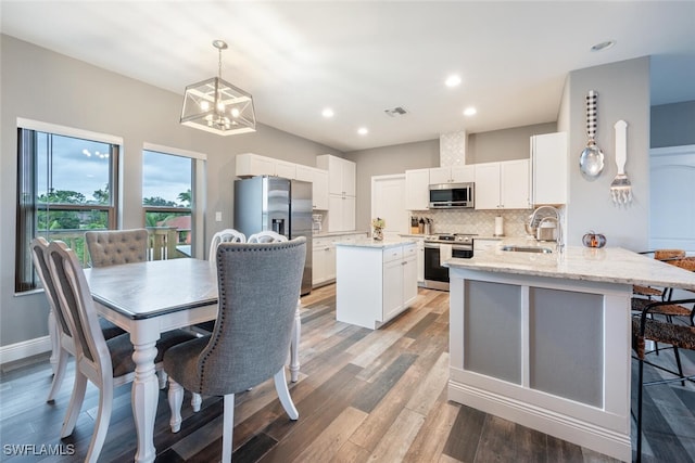 kitchen with kitchen peninsula, appliances with stainless steel finishes, decorative light fixtures, white cabinets, and sink