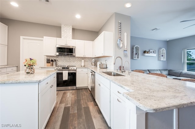 kitchen with sink, light stone countertops, stainless steel appliances, white cabinets, and dark hardwood / wood-style flooring