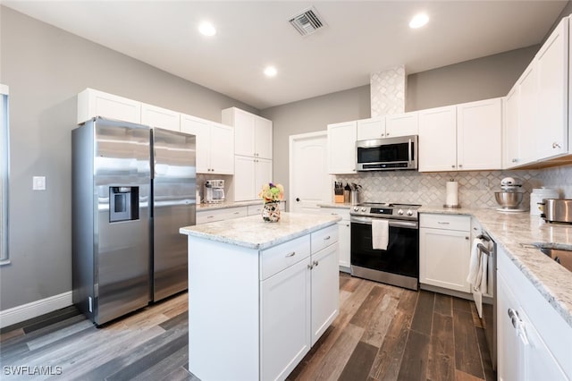 kitchen featuring dark wood-type flooring, appliances with stainless steel finishes, white cabinets, and a center island