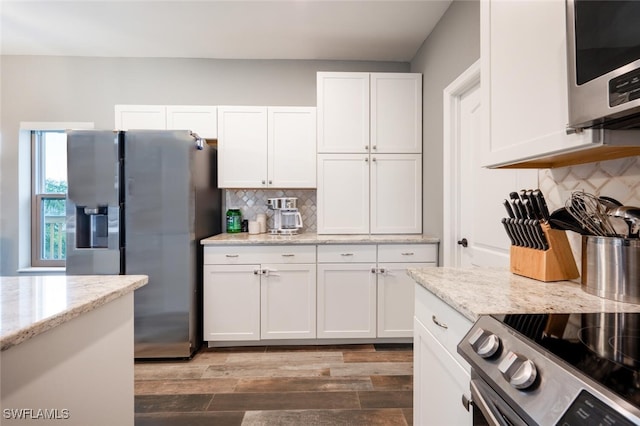 kitchen featuring light stone counters, backsplash, white cabinetry, and stainless steel appliances