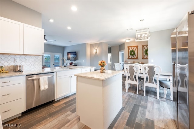 kitchen with decorative light fixtures, tasteful backsplash, sink, white cabinetry, and appliances with stainless steel finishes