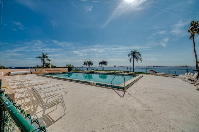 view of swimming pool featuring a water view and a patio