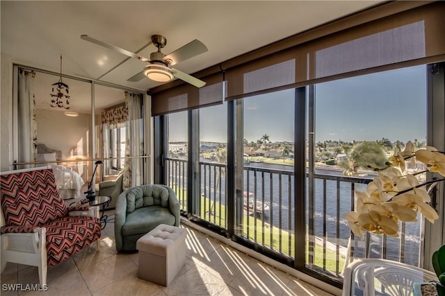 sunroom featuring ceiling fan and a water view