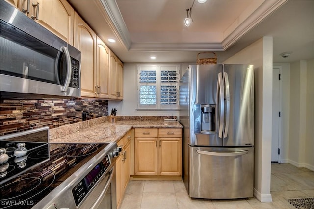 kitchen featuring light stone countertops, appliances with stainless steel finishes, light brown cabinets, decorative backsplash, and a raised ceiling