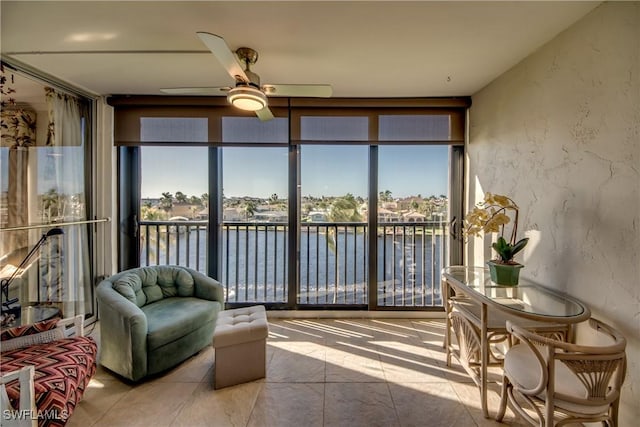 sunroom / solarium featuring ceiling fan and a water view